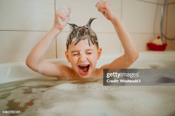 playful boy with spiked hair screaming in bathtub - boys taking a shower stock pictures, royalty-free photos & images