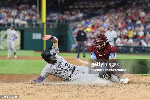 Ryan McMahon of the Colorado Rockies scores past J.T. Realmuto of the Philadelphia Phillies during the sixth inning at Citizens Bank Park on April...