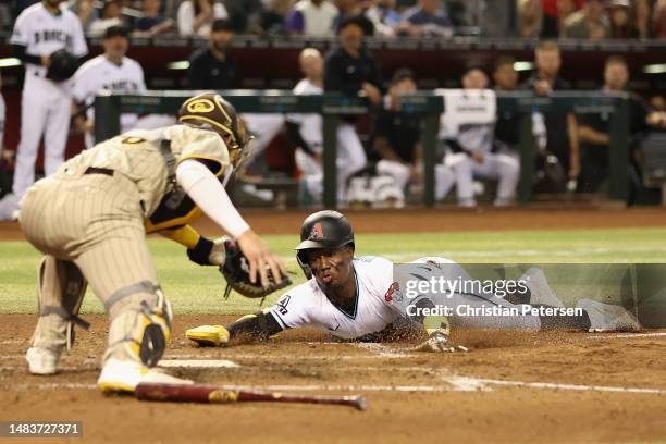 Geraldo Perdomo of the Arizona Diamondbacks dives into home plate to score a run past catcher Austin Nola of the San Diego Padres during the fourth...