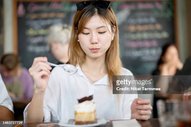 you can enjoy more variety of eating out in local restaurants. young women korean enjoy eating cake at local restaurants during visits to travel southeast asia. - gagged woman stock pictures, royalty-free photos & images