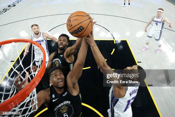Kevon Looney and Andrew Wiggins of the Golden State Warriors go for rebound against Keegan Murray of the Sacramento Kings during Game Three of the...