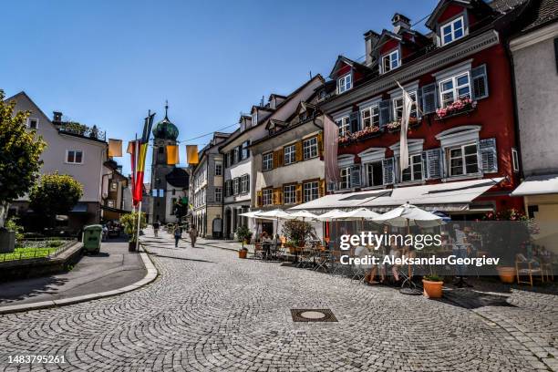 paved street along coffee bars and apartment buildings ending in seekapelle tower in bregenz, austria - österrikisk kultur bildbanksfoton och bilder