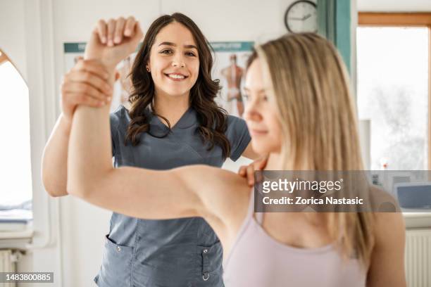 smiling physical therapist working with patient looking at camera - exercise pill stockfoto's en -beelden