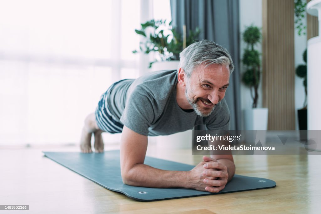 Smiling mature man working out at home.