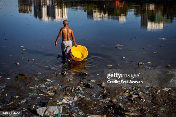 Fisherman collects moss for fishing as plastic waste floats in the waters of Manila Bay on April 19, 2023 in Manila, Philippines. The Philippines is...