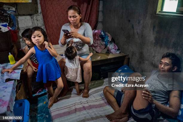 Rossnie Canubas and her husband Jonathan Agravio sit at home with their children on April 11, 2023 in Quezon city, Metro Manila, Philippines....