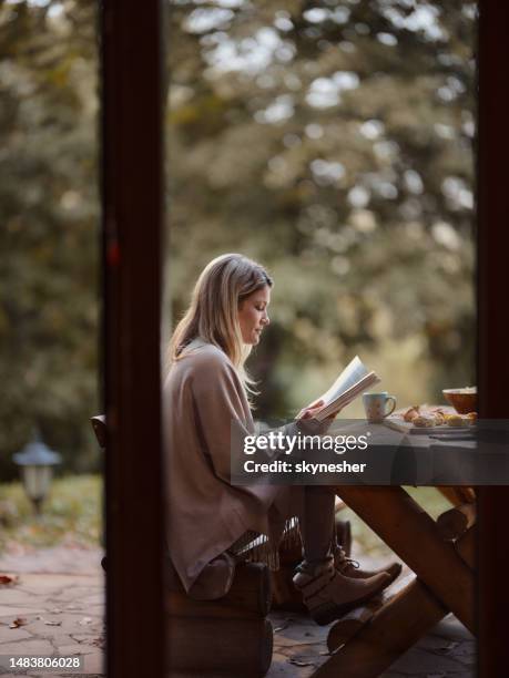 mujer relajada leyendo un libro en un día de otoño en un patio. - mujer leyendo libro en el parque fotografías e imágenes de stock