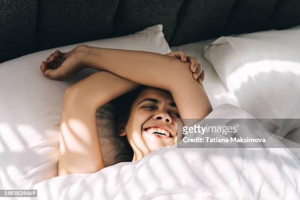 a beautiful young woman sleeps on white bedding in a hotel, light from the blinds on her face. - woman bedroom sleeping bildbanksfoton och bilder