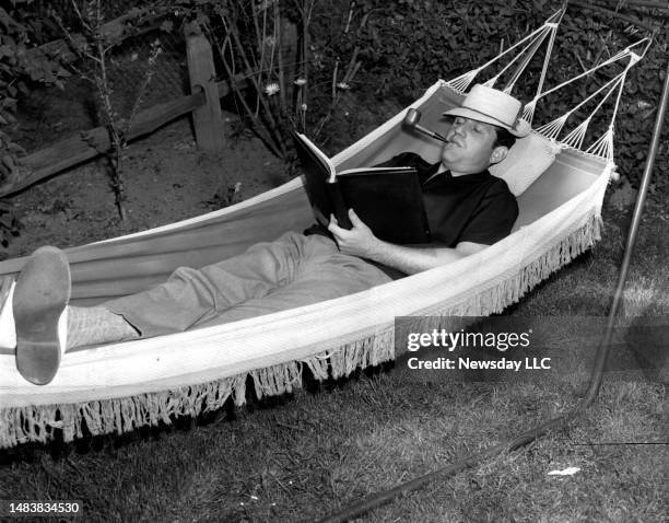 Rockville Centre, N.Y.: Comedian Alan King relaxes in a hammock while looking over a script at his home in Rockville Centre, New York on May 9, 1957.