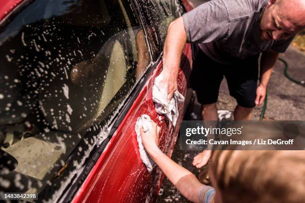 close up of father and son washing car together - car splashing water on people stock pictures, royalty-free photos & images