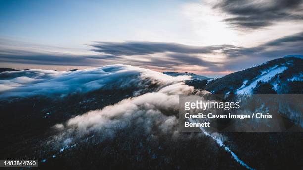 low winter clouds blanket snow covered saddleback mountain, maine - appalachia stock-fotos und bilder