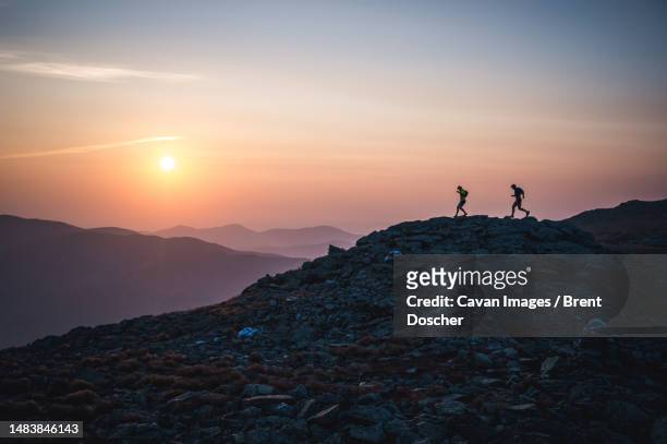 silhouette of male runners running down ridge at sunrise in mountains - summit of ibero american presidents day 2 stockfoto's en -beelden