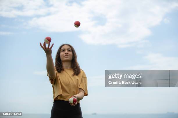 giovane donna giocoliere con cielo blu. - fare il giocoliere foto e immagini stock