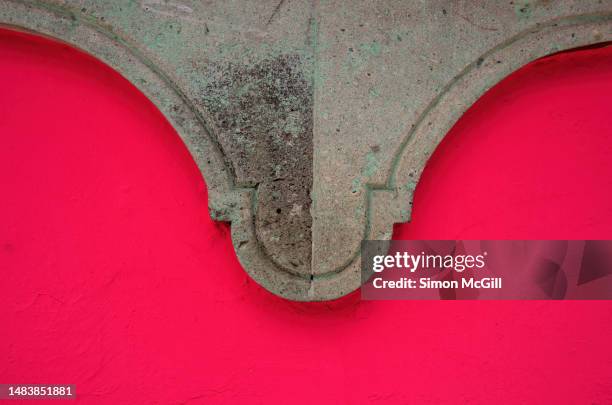 relief carved stone decoration underneath a window on a colonial building painted vivid pink - architectural cornice stock-fotos und bilder