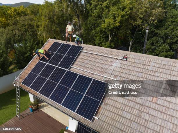 three engineers installing solar panels on roof - houses in the sun stock pictures, royalty-free photos & images