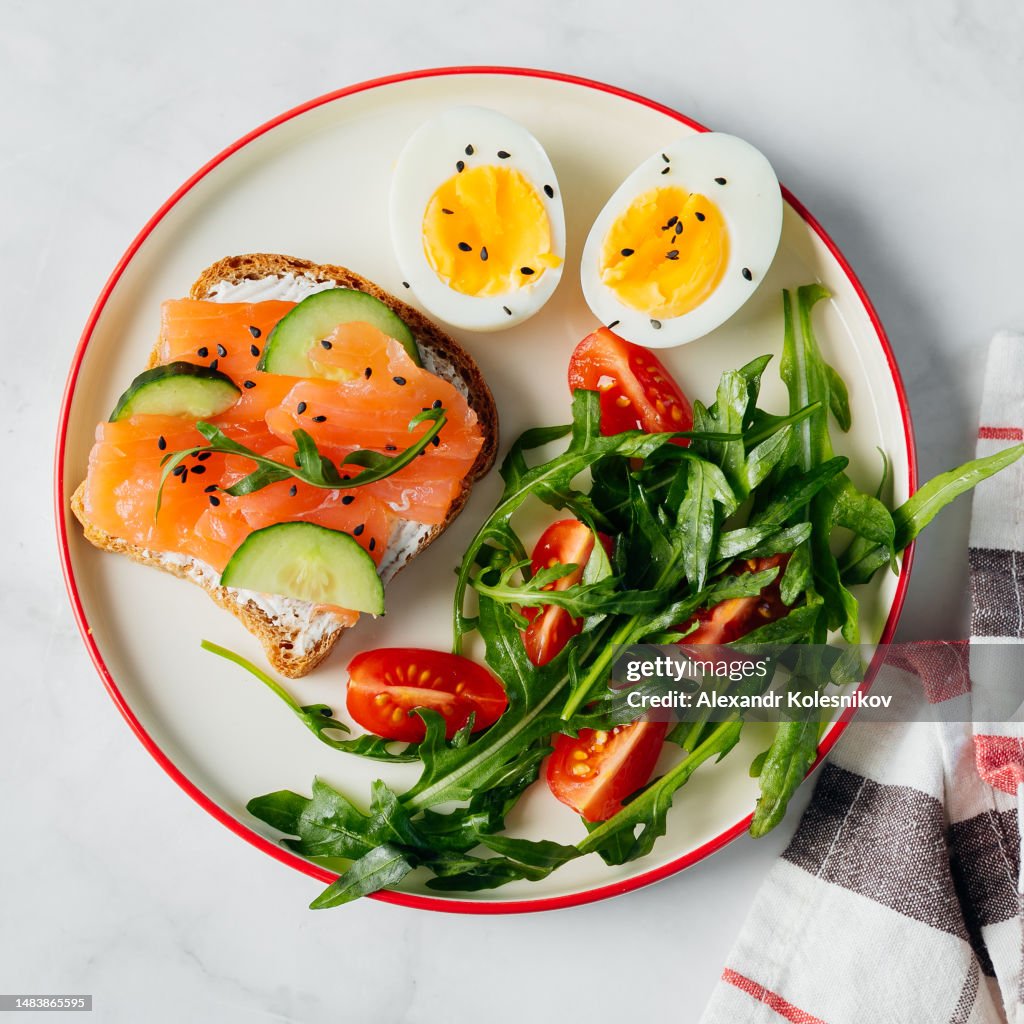 Healthy breakfast lunch. Plate with sandwiches with salted salmon, cucumber, arugula, tomatoes and eggs. Organic balanced food. Healthy food. Top view.