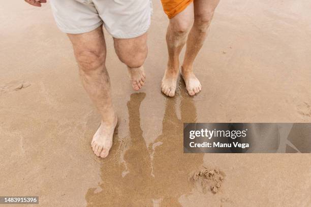 crop man walking on sandy beach - old man feet stock pictures, royalty-free photos & images