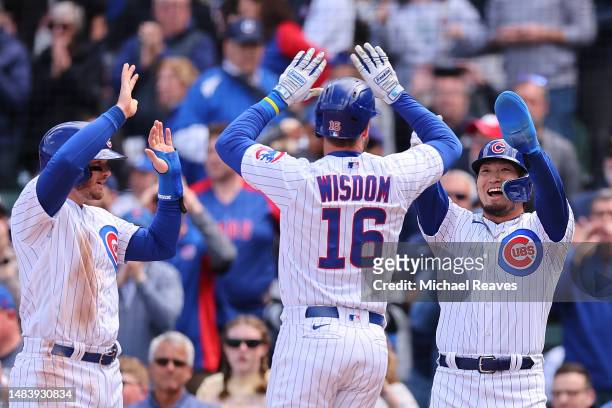 Patrick Wisdom of the Chicago Cubs high fives Ian Happ and Seiya Suzuki after hitting a three-run home run off Jake Reed of the Los Angeles Dodgers...