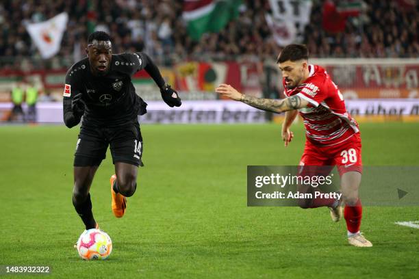 Silas Katompa Mvumpa of VfB Stuttgart avoids Davide Colina of FC Augsburg during the Bundesliga match between FC Augsburg and VfB Stuttgart at...