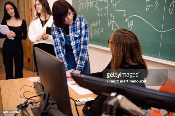transgender female college student at teacher desk in classroom. - blackboard qc stock pictures, royalty-free photos & images