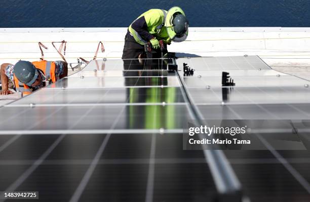 Workers install solar panels during the completion phase of a 4-acre solar rooftop atop AltaSea's research and development facility at the Port of...