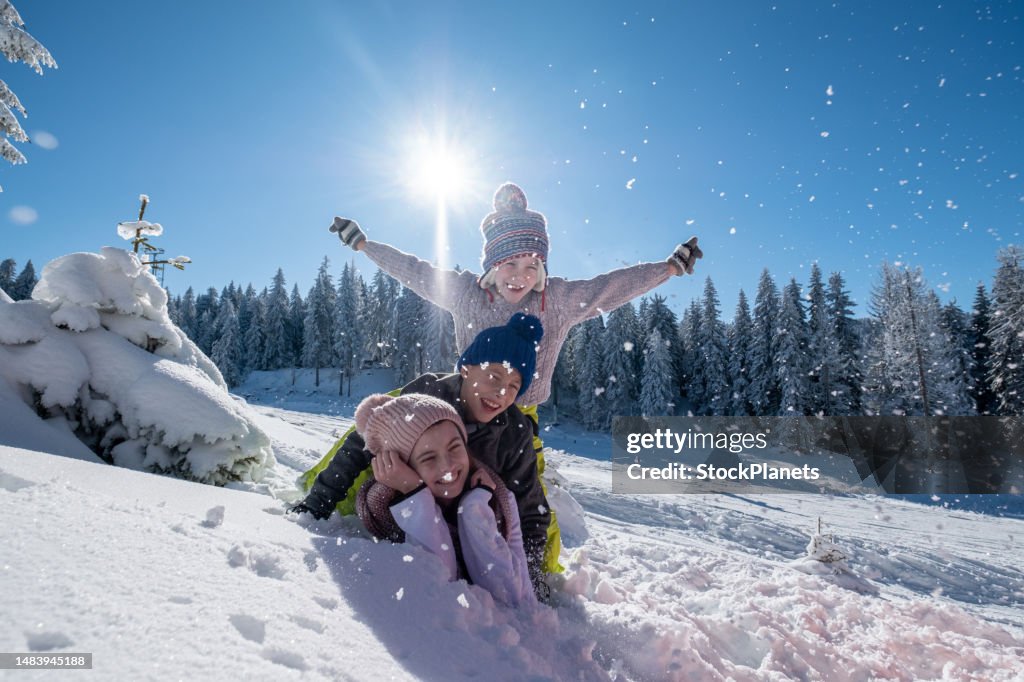 Children are lying on top of each other in the snow