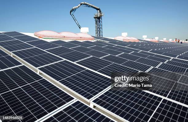 Workers stand between solar panels during the completion phase of a 4-acre solar rooftop atop AltaSea's research and development facility at the Port...