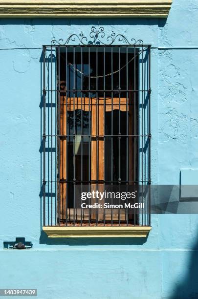 ornate metal security grill over a double window on a spanish colonial style house painted light blue - sicherheitsgitter stock-fotos und bilder