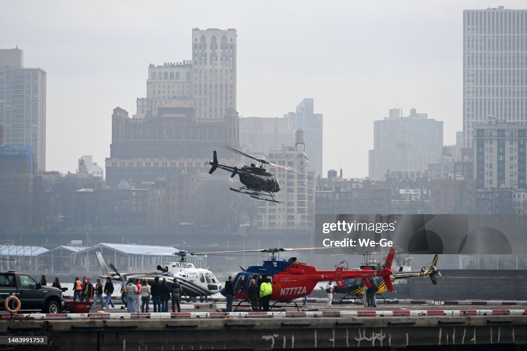 A Bell 407 helicopter "Helicopter Services" (N403TD) and a Bell 407 GXP helicopter of "ZIP AVIATION" (N777ZA) on the helipad at Downtown Manhattan Heliport, 6 East River Piers. East River and Brooklyn in the background