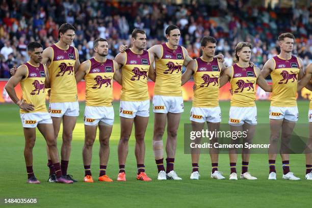 Lions players line up during an ANZAC ceremony during the round six AFL match between Greater Western Sydney Giants and Brisbane Lions at Manuka...