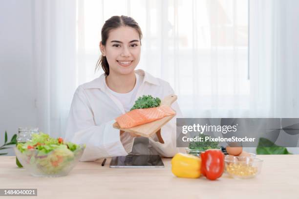 female nutritionist holding fresh raw salmon which contain high protein good fat and omega-3s. - high fibre diet stock pictures, royalty-free photos & images