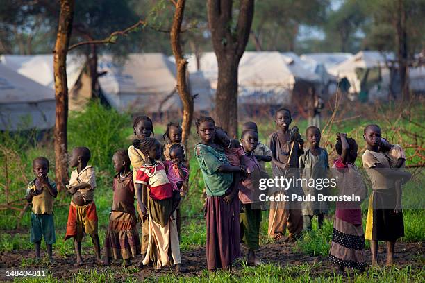 Sudanese refugee children stand near their tents in a muddy field July 15, 2012 in Jamam refugee camp, South Sudan. Up to 16,000 refugees are in the...