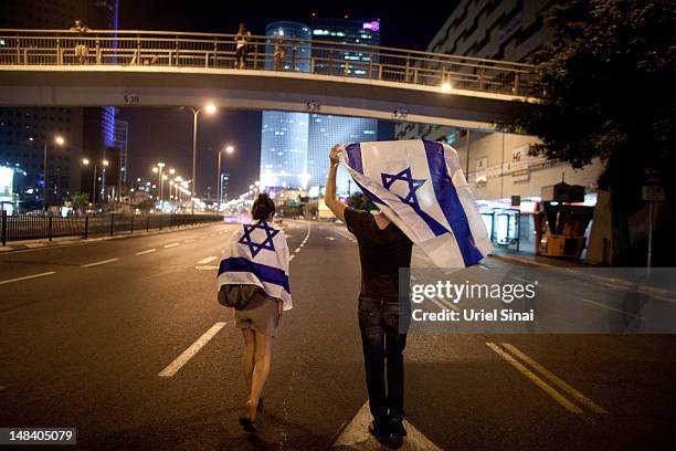 Israelis wave their national flag as they march through the streets to protest rising housing costs on July 15, 2012 in Tel Aviv, Israel. Growing...