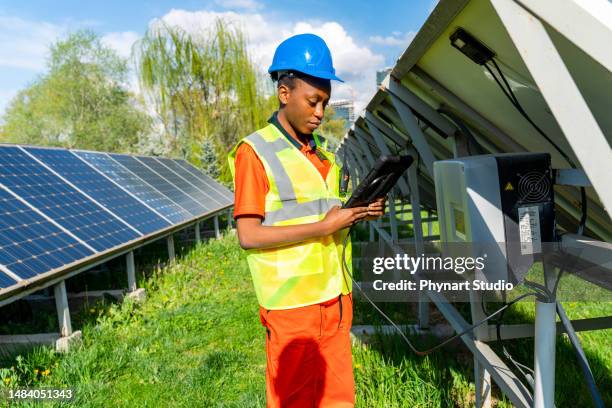 the solar farm (solar panel) with black female engineers check the operation of the system - lucht en ruimtevaartingenieur stockfoto's en -beelden