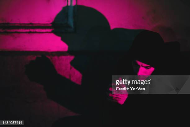 dark atmospheric portrait with dramatic shadow of a depressed young man sitting alone in the neon night city. contemplating suicide - photos of suicide victims 個照片及圖片檔