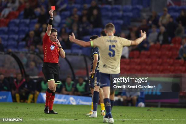 Referee Shaun Evans gives Carl Jenkinson of the Jets a red card as Matthew Jurnman of the Jets reacts during the round 25 A-League Men's match...