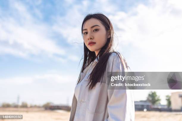 retrato da bela mulher jovem, roupas casuais e mochila, andando na grama seca, olhando para a câmera e sorrindo - south korean models - fotografias e filmes do acervo