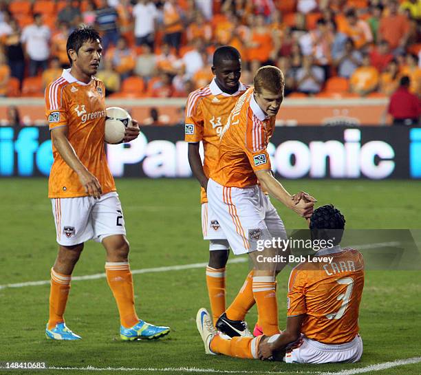 Andre Hainault of the Houston Dynamo helps up Calen Carr after he was taken down in the penalty area against the D.C. United at BBVA Compass Stadium...