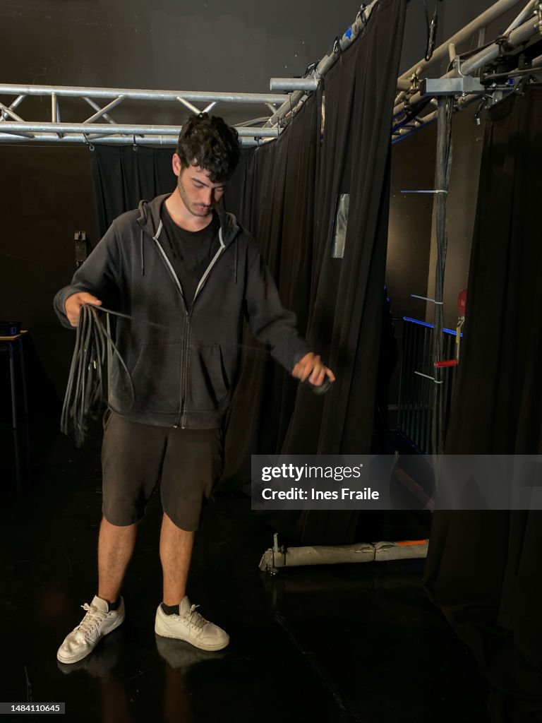 Sound and lighting technician picking up cables from the theater stage