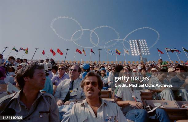 Smoke rings in the form of the Olympic Rings above flags of participating nations and spectators at the opening ceremony of the 1984 Summer Olympics,...