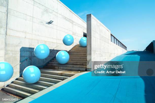 digital 3d picture of a group of blue spheres moving down in a minimal concrete architecture with blue paint floor. - force physics stock pictures, royalty-free photos & images