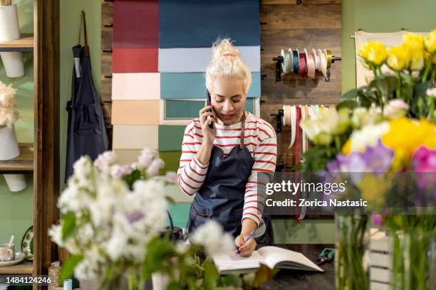 beautiful woman is working in flower shop taking order - multi platinum selling stock pictures, royalty-free photos & images