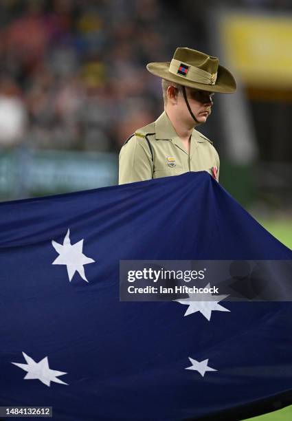 Member of the Australian Army is seen holding the flag during ANZAC Day commemorations prior to the round eight NRL match between North Queensland...