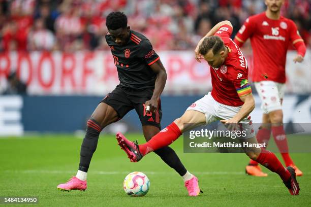 Alphonso Davies of FC Bayern Munich is challenged by Silvan Widmer of 1.FSV Mainz 05 during the Bundesliga match between 1. FSV Mainz 05 and FC...