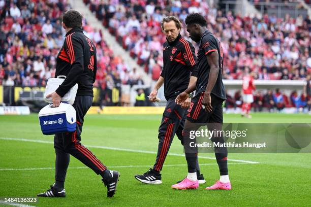 Alphonso Davies of FC Bayern Munich receives medical treatment before being substituted off during the Bundesliga match between 1. FSV Mainz 05 and...