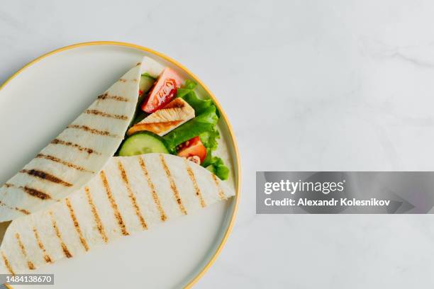 fresh tortilla wraps with chicken and fresh vegetables on plate. healthy eating. directly above - lavash stockfoto's en -beelden