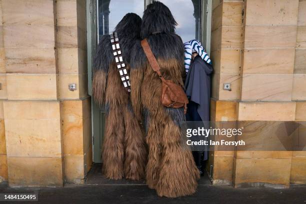 Two Chewbacca characters from Star Wars look through a cafe window on the first day of the Scarborough Sci-Fi weekend on April 22, 2023 in...