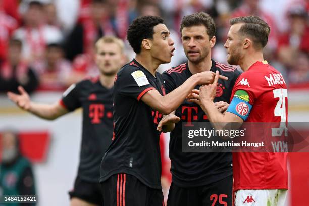 Jamal Musiala and Thomas Mueller of FC Bayern Munich clash with Silvan Widmer of 1.FSV Mainz 05 during the Bundesliga match between 1. FSV Mainz 05...