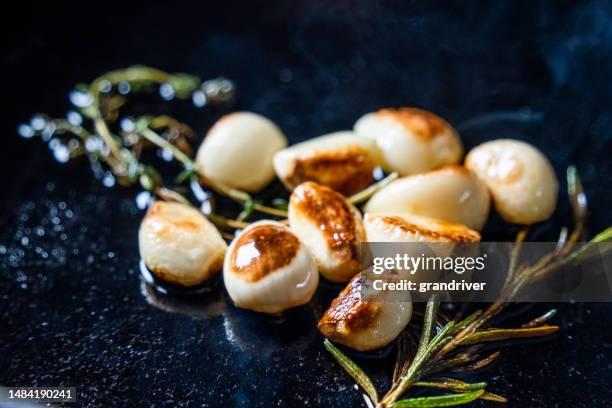 sautéed garlic cloves cooked to perfection on a cast iron skillet, infusing a bold and flavorful taste to any dish. a versatile and essential ingredient in many cuisines - sudderen stockfoto's en -beelden