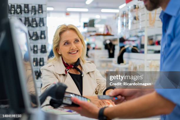 a mulher está dentro da loja fazendo compras para seus cuidados, enquanto ela é atendida por um caixa homem da loja. - color tipo de imagen - fotografias e filmes do acervo